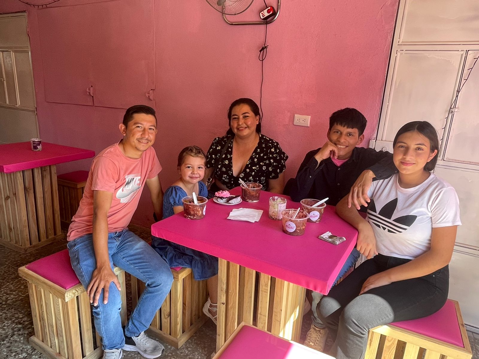 Una imagen de la perspectiva de una cámara de seguridad donde se miran varias personas sentadas alrededor de varias mesas, conviviendo unas con otras mientras disfrutan su comida